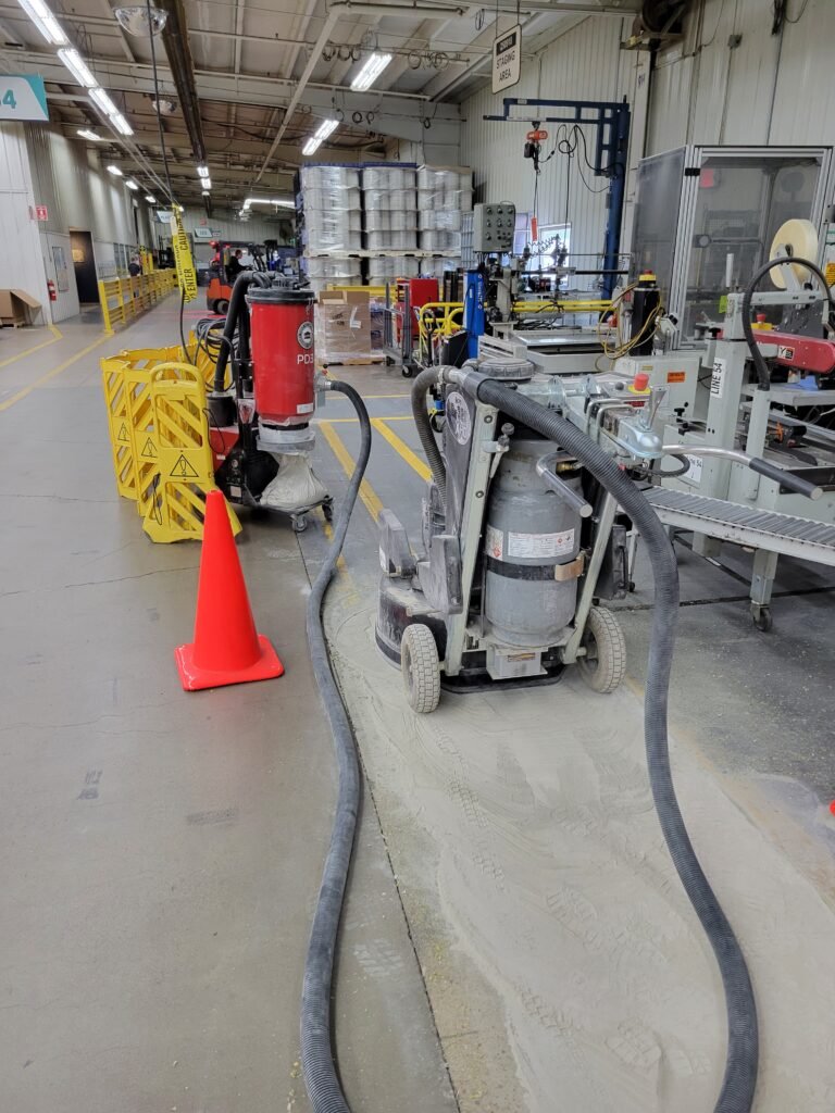 A concrete polishing machine grinding off the old coating to reveal the smooth concrete beneath.