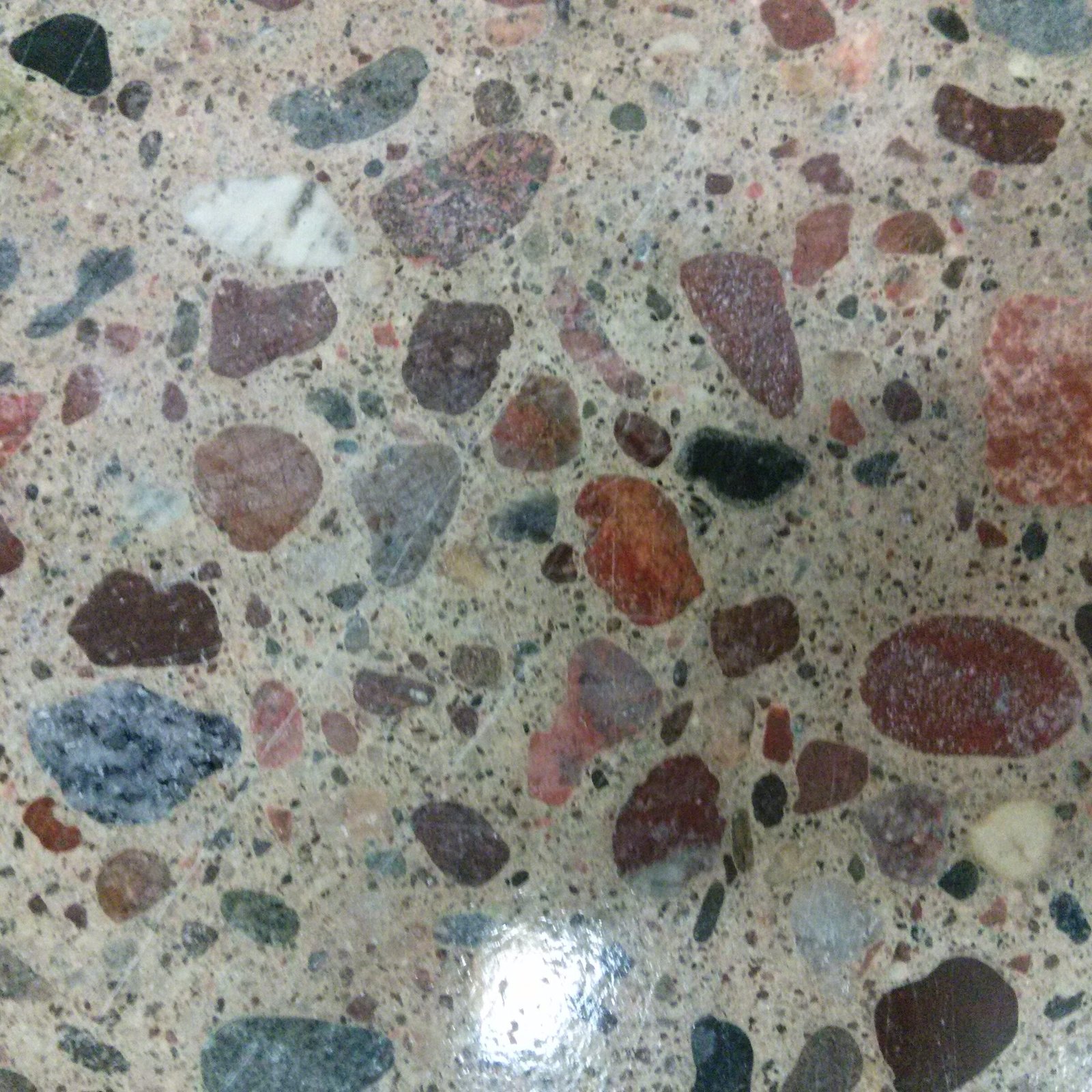 Close up of a polished concrete floor with large aggregate exposure showing slight reflectivity of the floor but moreso the exposed stones.